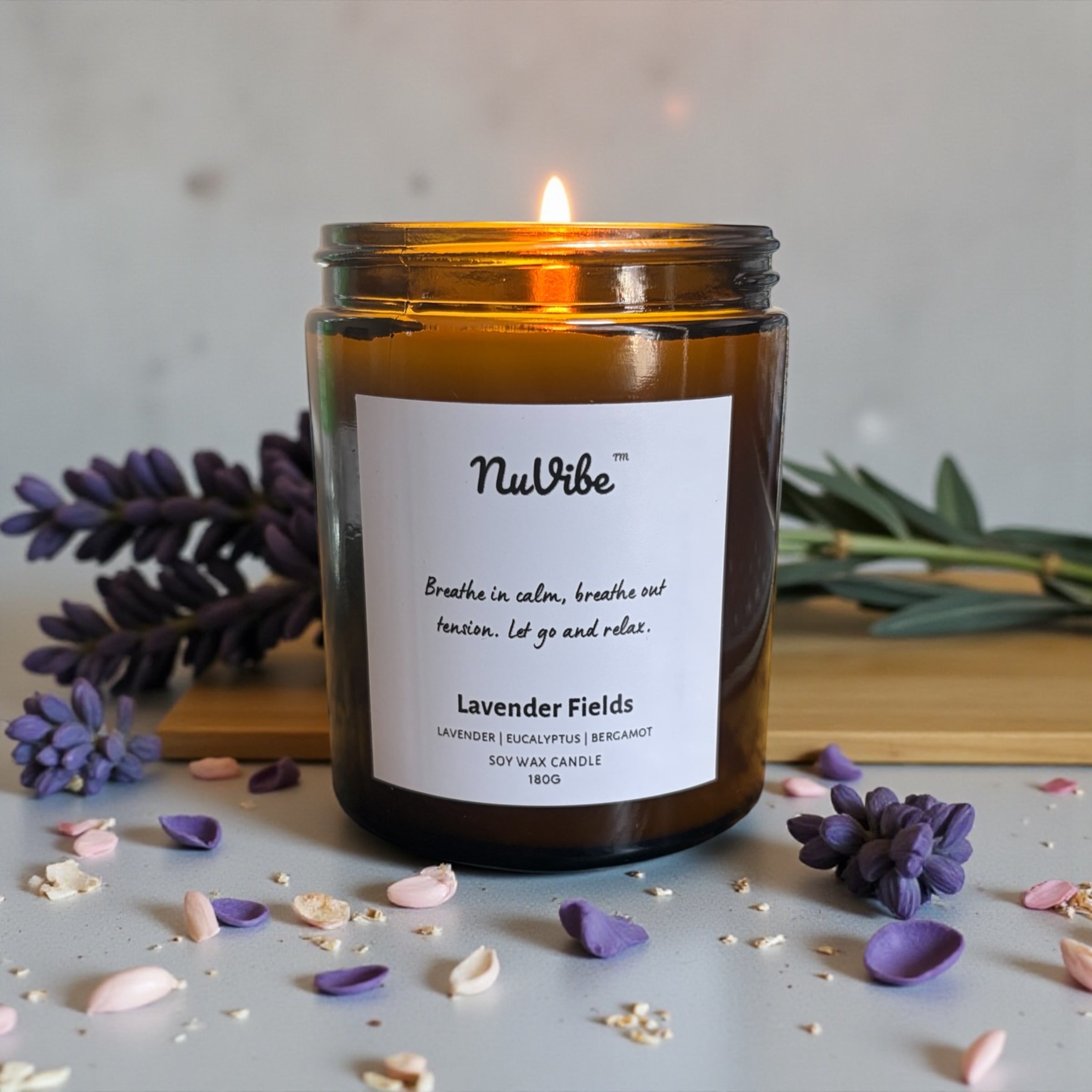 Top view of NuVibe lavender soy wax candle in amber jar styled with fresh lavender, calming essential oil candle for relaxation and sleep