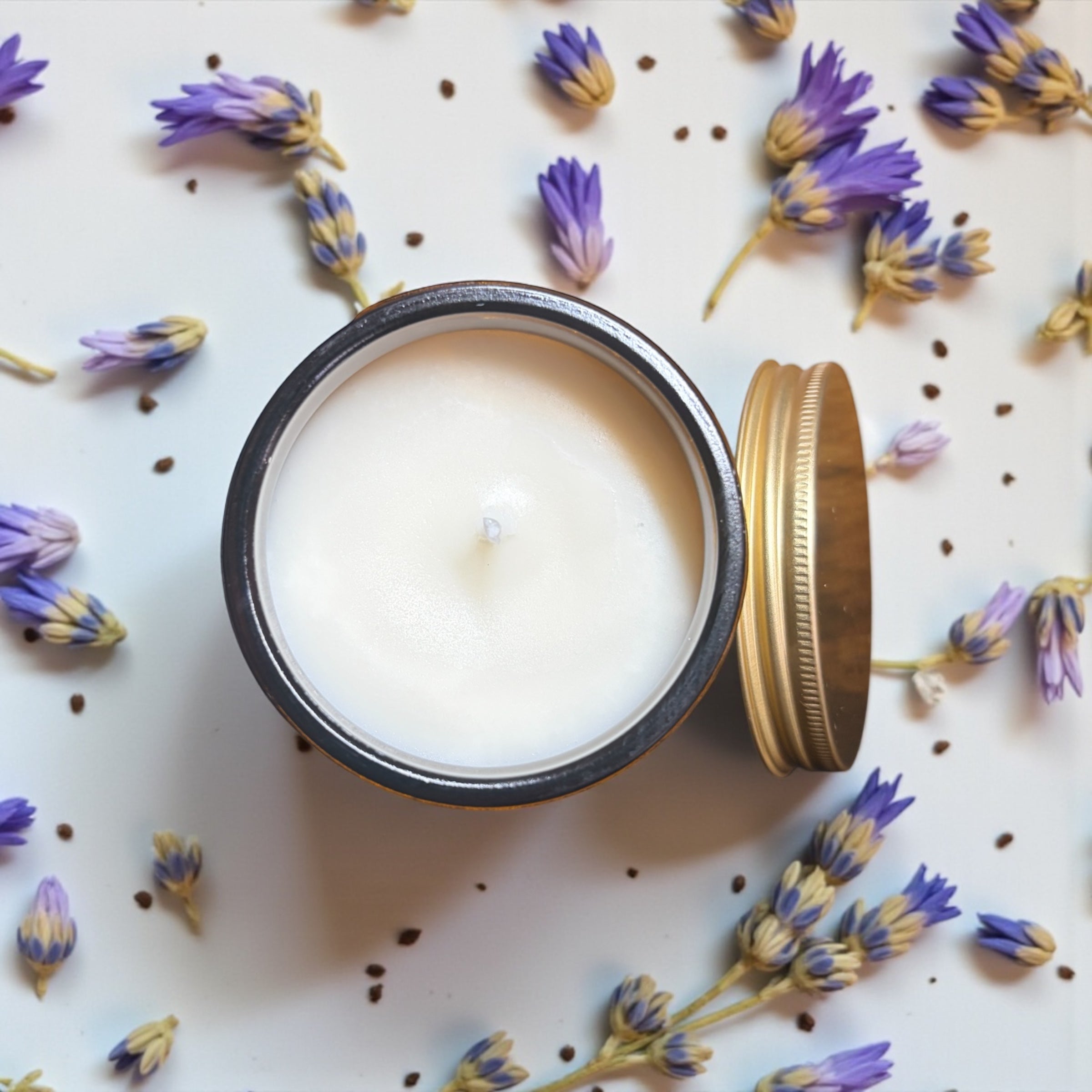 Minimal flat lay of NuVibe amber glass soy candle surrounded by lavender stems, luxury natural candle for calm evenings and self-care