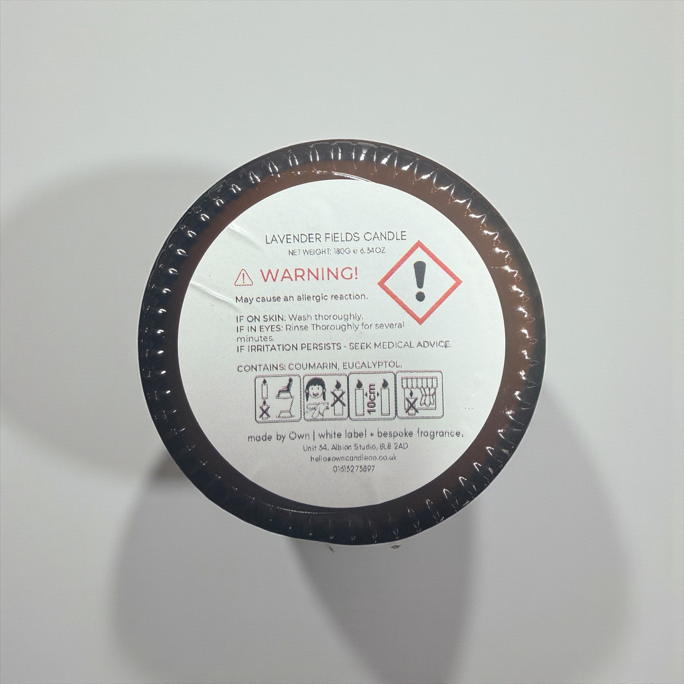 Bottom view of NuVibe soy wax candle showing safety instructions label, ingredients, burn time and care guide on amber glass jar