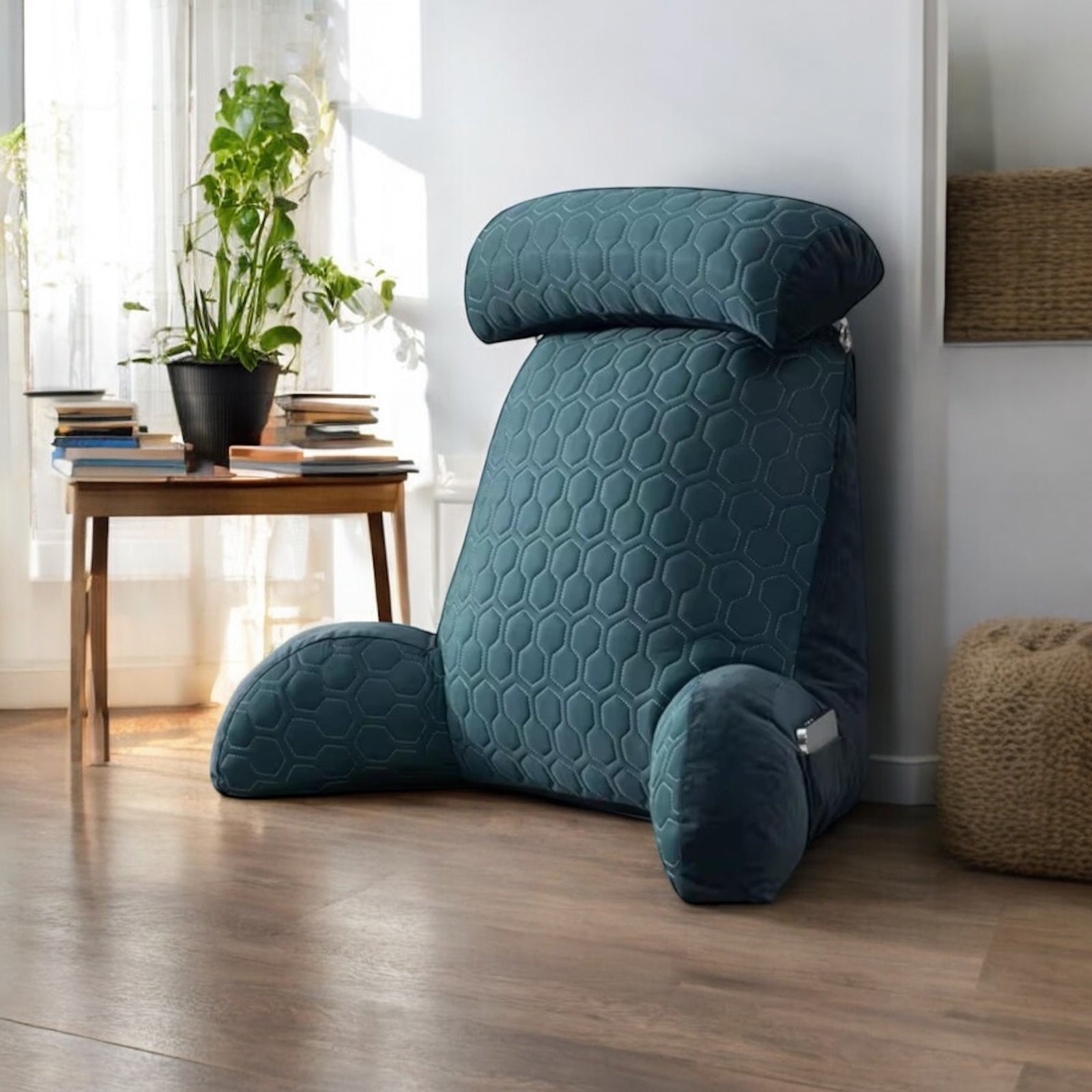 Cushion on the floor next to a table with books on top. 