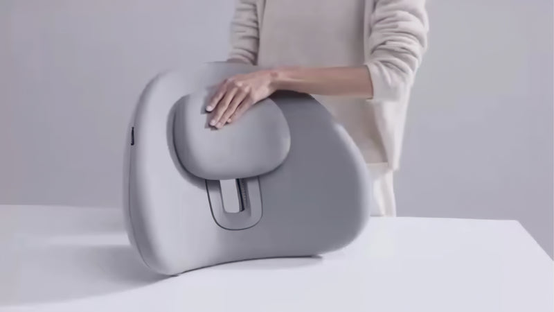 Video of a woman seated in a car using an ergonomic back support cushion with an adjustable padded section for added comfort.
